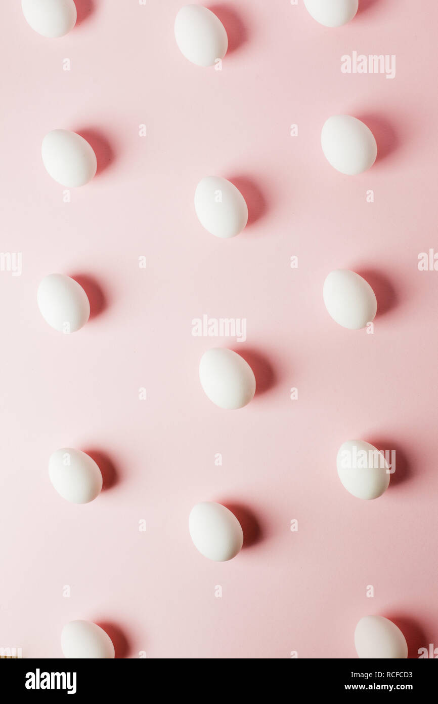 Huevos de color blanco sobre un fondo de color rosa claro con el reflejo de las sombras y copie el espacio. Diseño para la pascua. Sentar planas, patrón Foto de stock