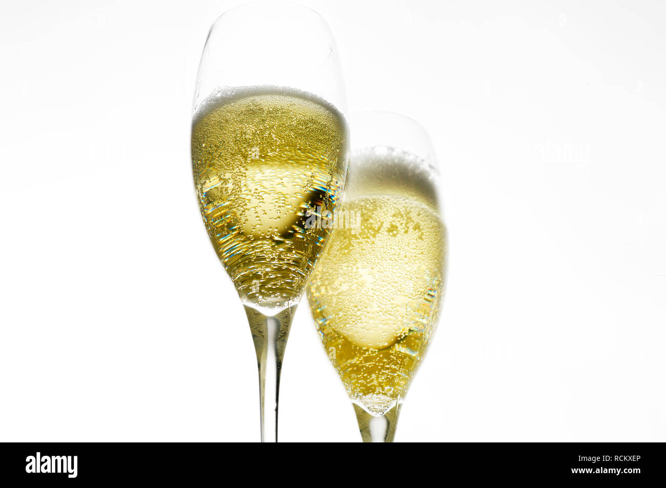 Brindis de celebración con dos copas de champaña, iluminada desde atrás, fondo liso Foto de stock