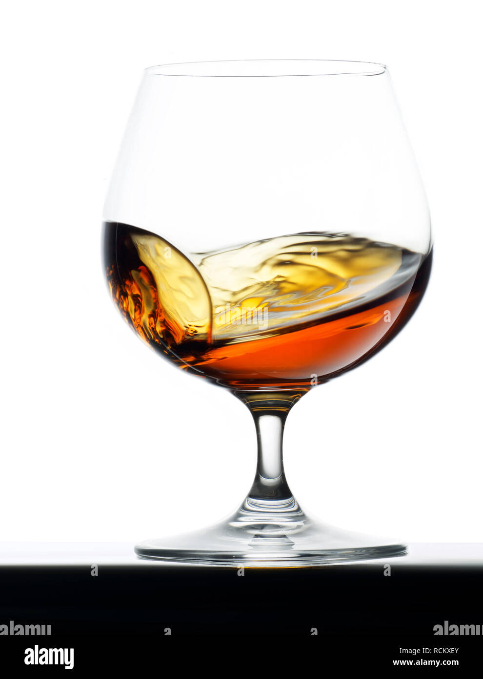 Copa de coñac brandy, iluminada desde atrás, fondo liso, longitud completa Foto de stock