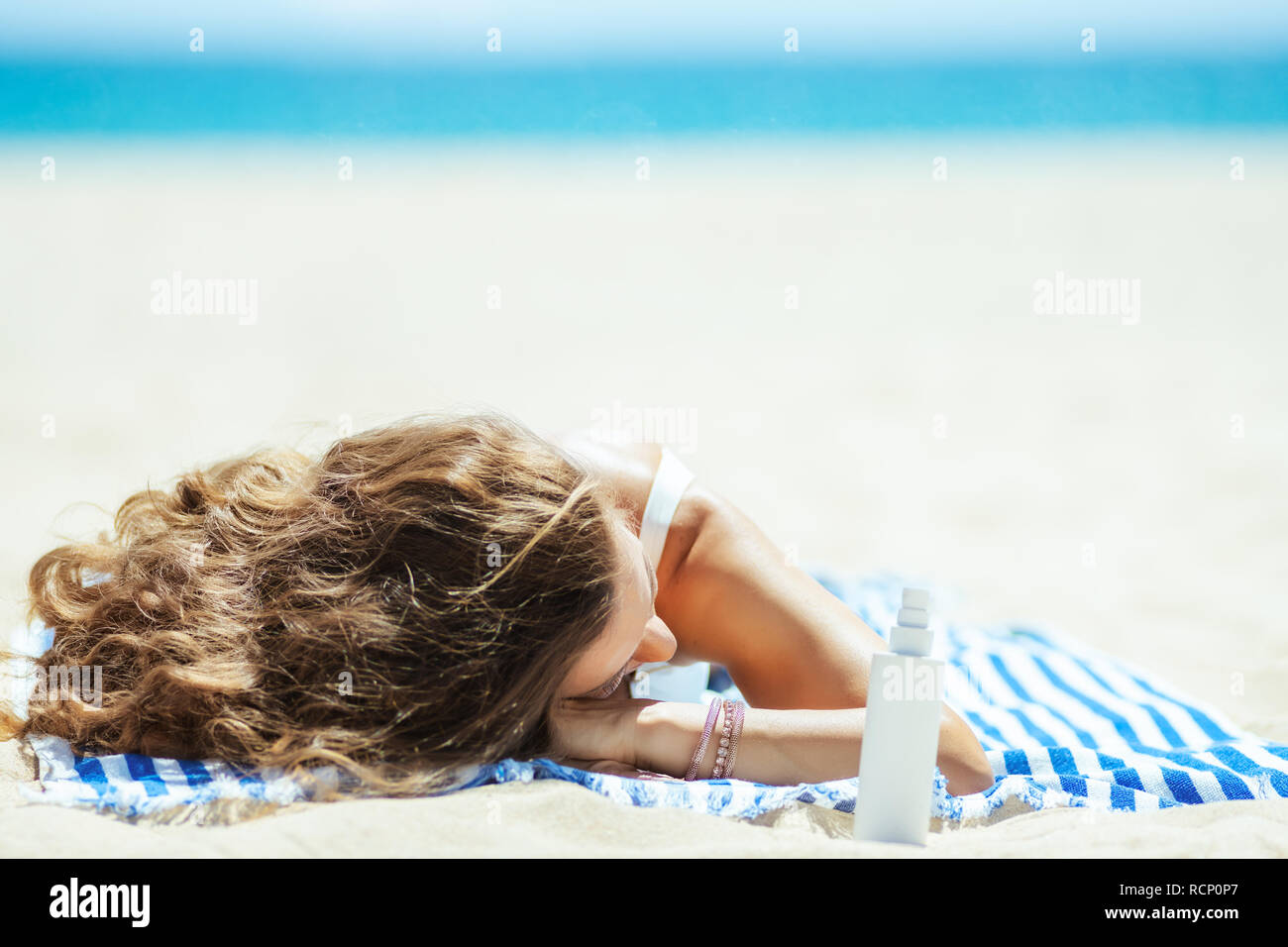 Mujer sana en trajes de baño blanco con bronceadores recostada sobre una  toalla de rayas en el Seacoast. filtro solar SPF o repelente o picadura de  insecto remediar o Fotografía de stock -