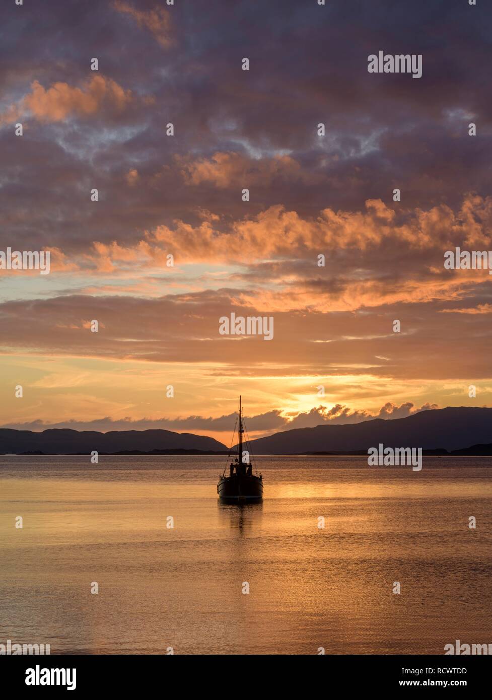 La puesta de sol sobre el mar y una barca de madera Crinan, Escocia, Gran Bretaña Foto de stock