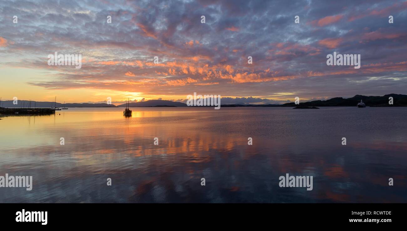 La puesta de sol sobre el mar y una barca de madera Crinan, Escocia, Gran Bretaña Foto de stock