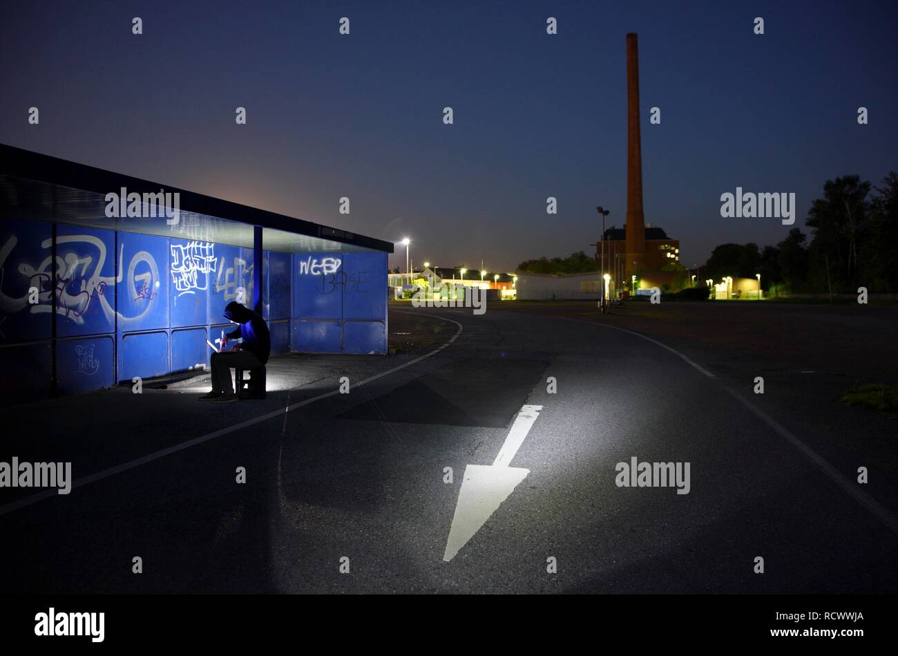 El hombre navegando en un ordenador portátil en una parada de autobús por la noche, la imagen simbólica de la piratería informática, los delitos informáticos, cibercriminalidad Foto de stock