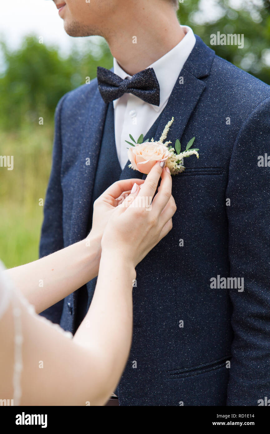 Atribuye la novia al novio un ojal en la solapa de la chaqueta Fotografía  de stock - Alamy