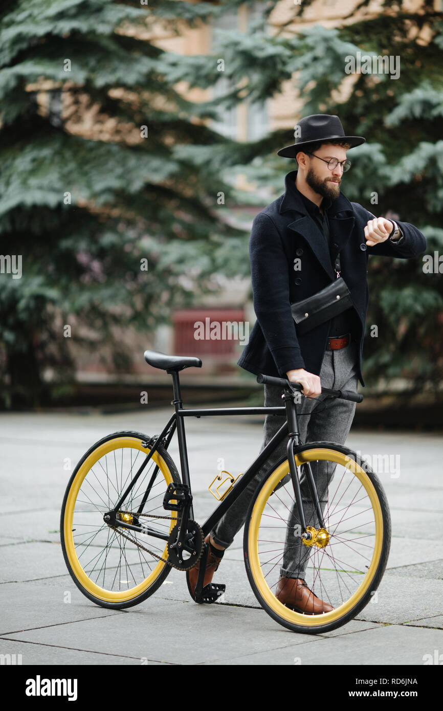 Guapo hipster disfrutando de un paseo en bici y controlar el tiempo en su  reloj Fotografía de stock - Alamy