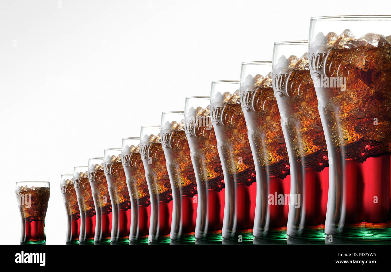 Vasos de Coca Cola con hielo, en una fila sobre un fondo blanco. Foto de stock