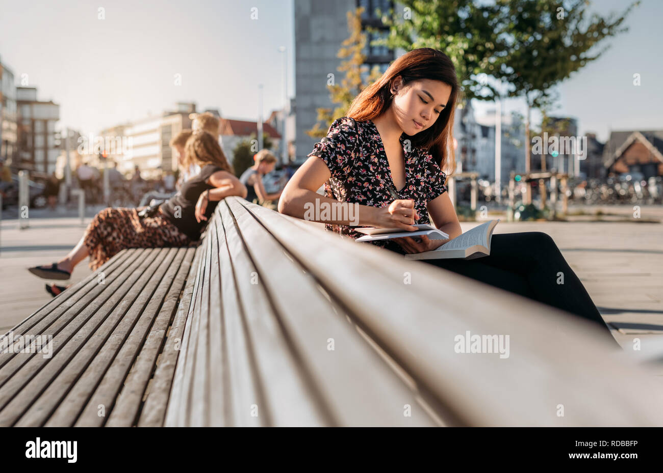 Estudiante universitario de Asia sentado en un banco del campus estudiando Foto de stock