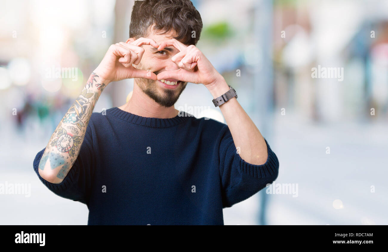 Joven apuesto hombre sobre fondo aislado haciendo forma de corazón con la  mano y los dedos sonriendo mirando a través de la inscripción Fotografía de  stock - Alamy