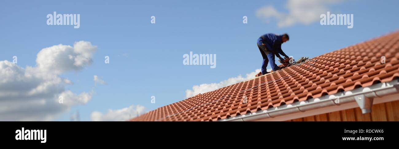 Banner web Hintergrund. Dachdecker, Bauarbeiter männlich, in der Sonne beim Dach reparieren oben auf dem Haus Foto de stock