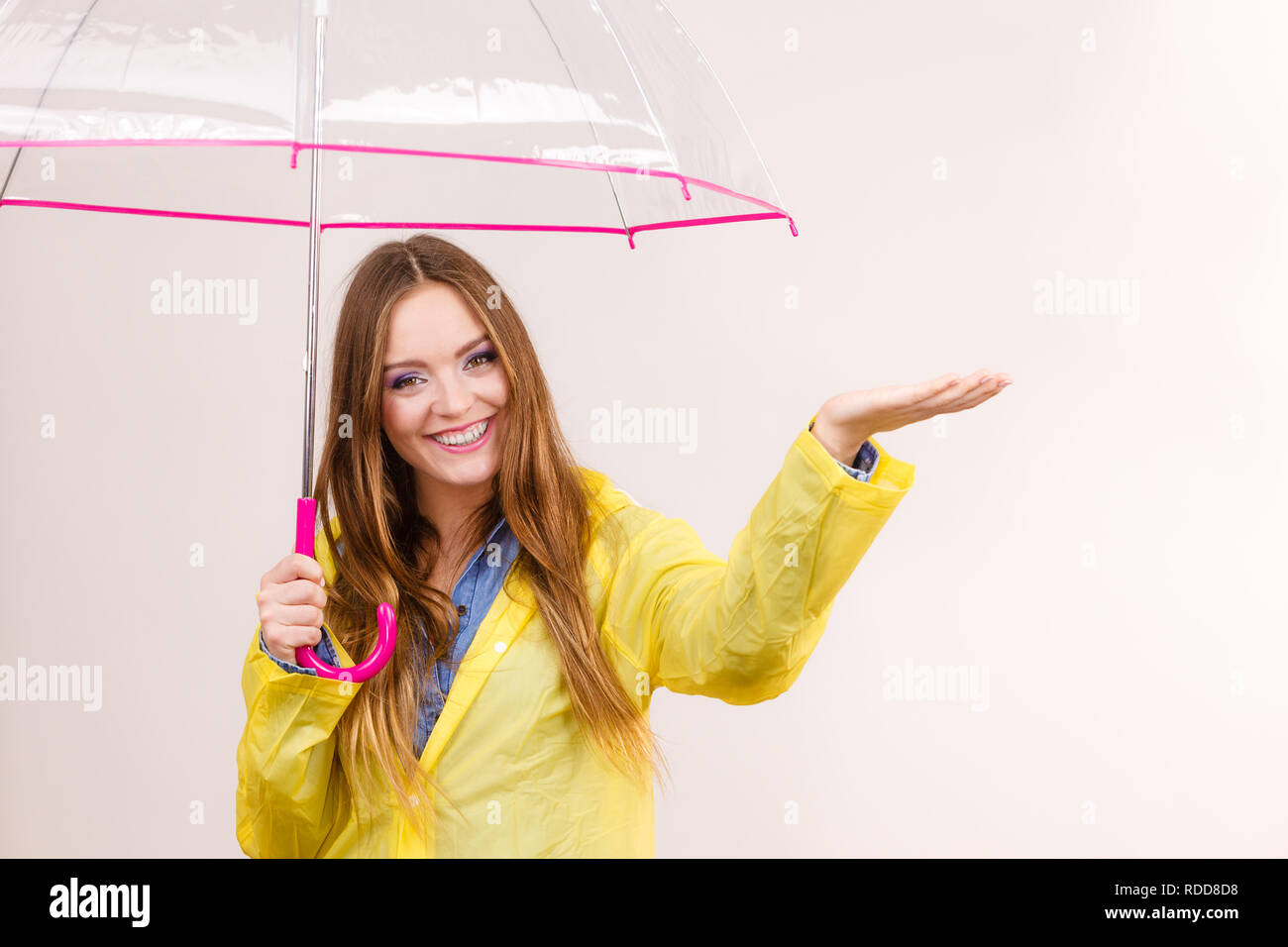 Mujer joven de lluvias en impermeable capa amarilla de pie con paraguas  transparente estirando el brazo, mantiene su palm para recoger agua de  lluvia. Previsión Fotografía de stock - Alamy