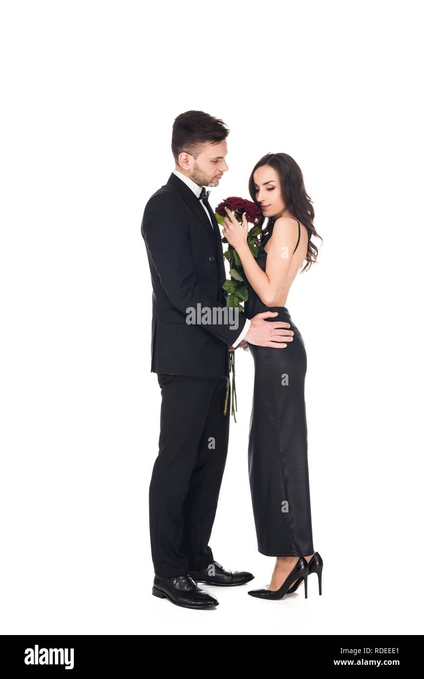 Atractiva pareja elegantes vestidos negro posando con rosas rojas en San Valentín, aislado en blanco Fotografía de stock - Alamy