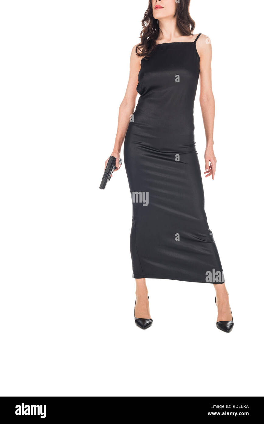 Vista recortada del agente secreto en femenino vestido negro sujetando la pistola, aislado en blanco Foto de stock