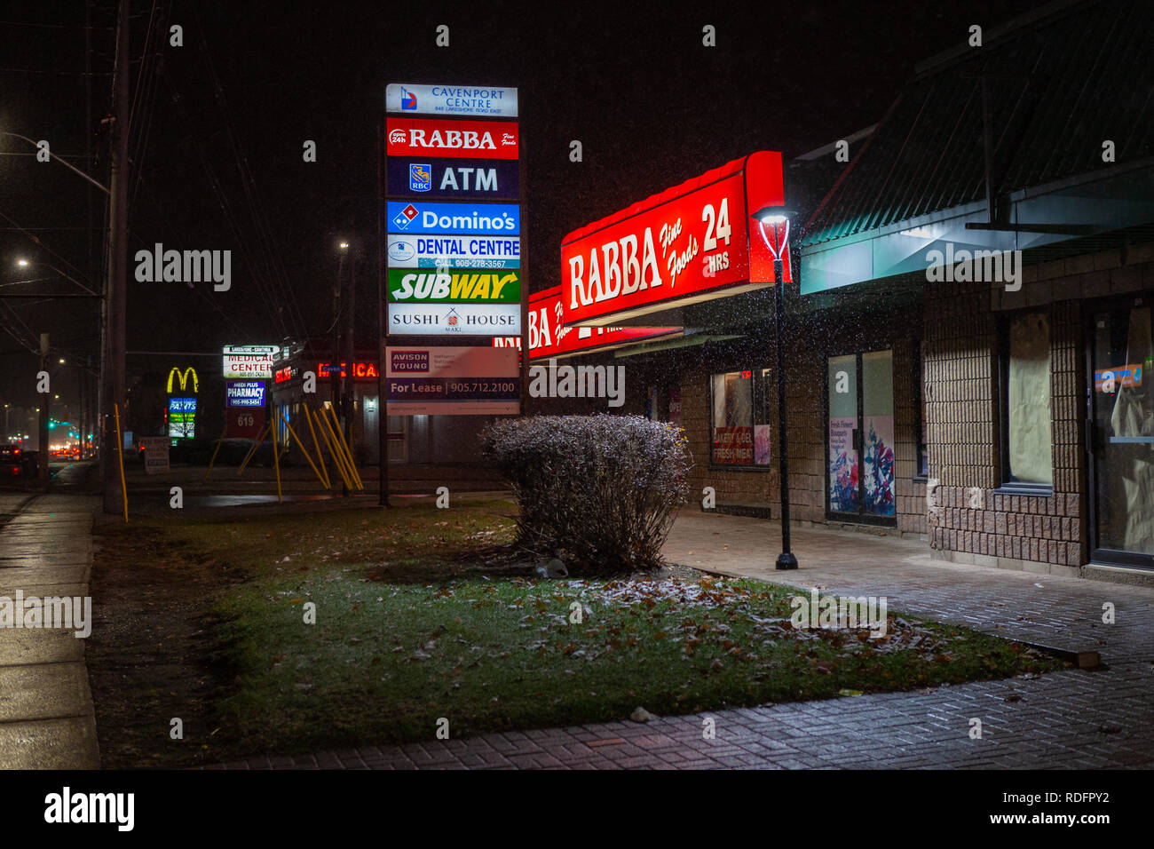 Toronto, Canada - December 4th, 2019: espectacular noche lluviosa con calles desiertas y reflejando los semáforos por tienda iluminada Foto de stock
