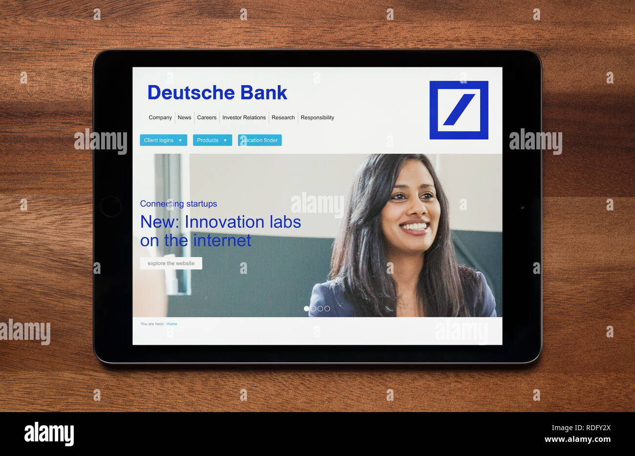 El sitio web de Deutsche Bank es visto en un iPad, que descansa sobre una mesa de madera (uso Editorial solamente). Foto de stock