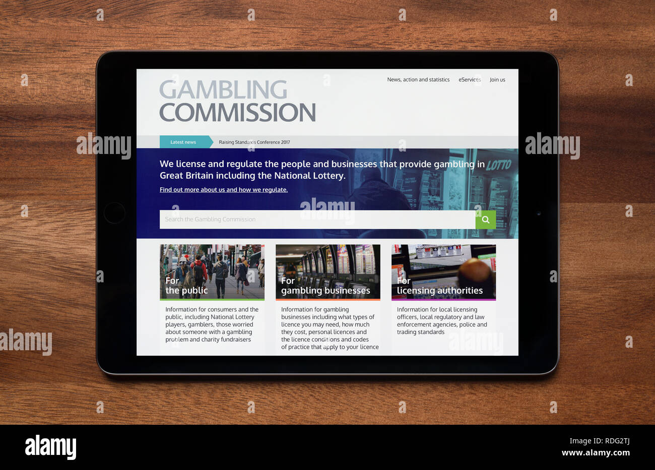La página web de Gambling Commission es visto en un iPad, que descansa sobre una mesa de madera (uso Editorial solamente). Foto de stock