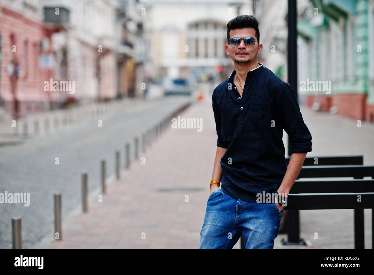 Elegante modelo indio, hombre en ropa casual, camisa negra y gafas de sol  que plantean en la calle exterior de la India Fotografía de stock - Alamy