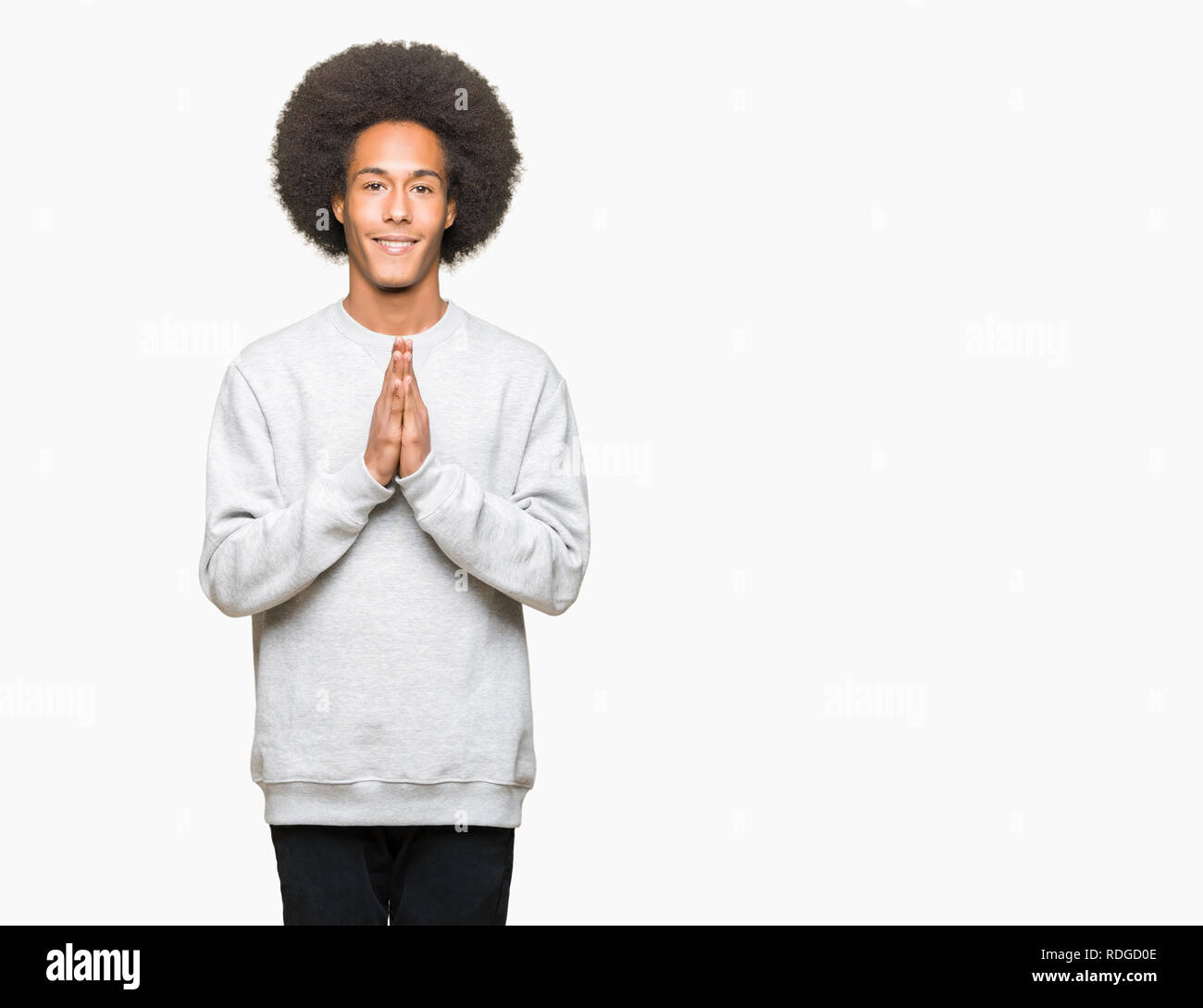 Joven hombre afroamericano con el cabello afro vistiendo sudadera deportiva  rezando con las manos juntas pidiendo perdón sonriendo confiada Fotografía  de stock - Alamy