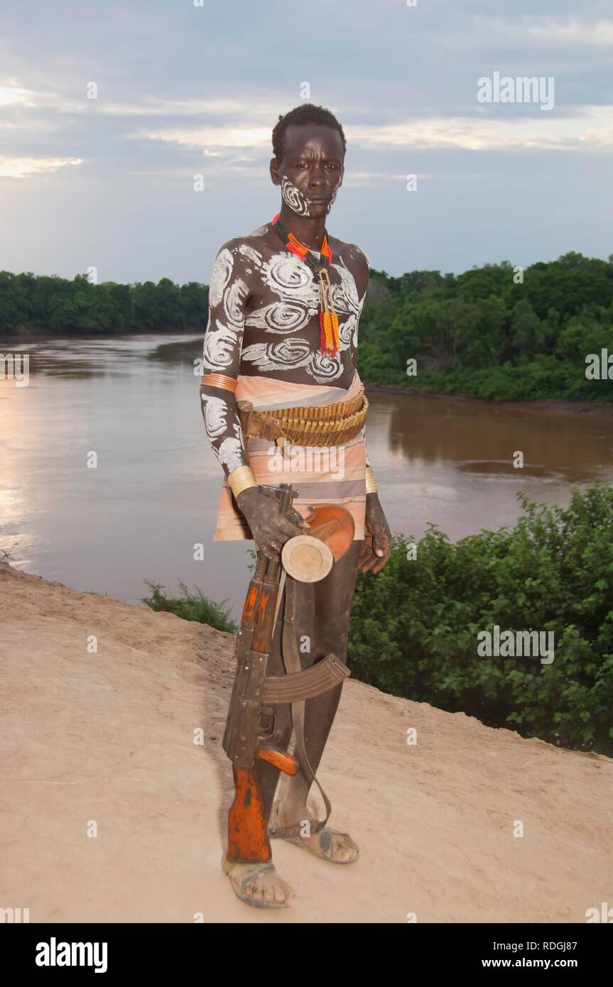 Karo warrior con pinturas faciales y corporales y un rifle, al sur del valle de Omo, Etiopía meridional, África Foto de stock