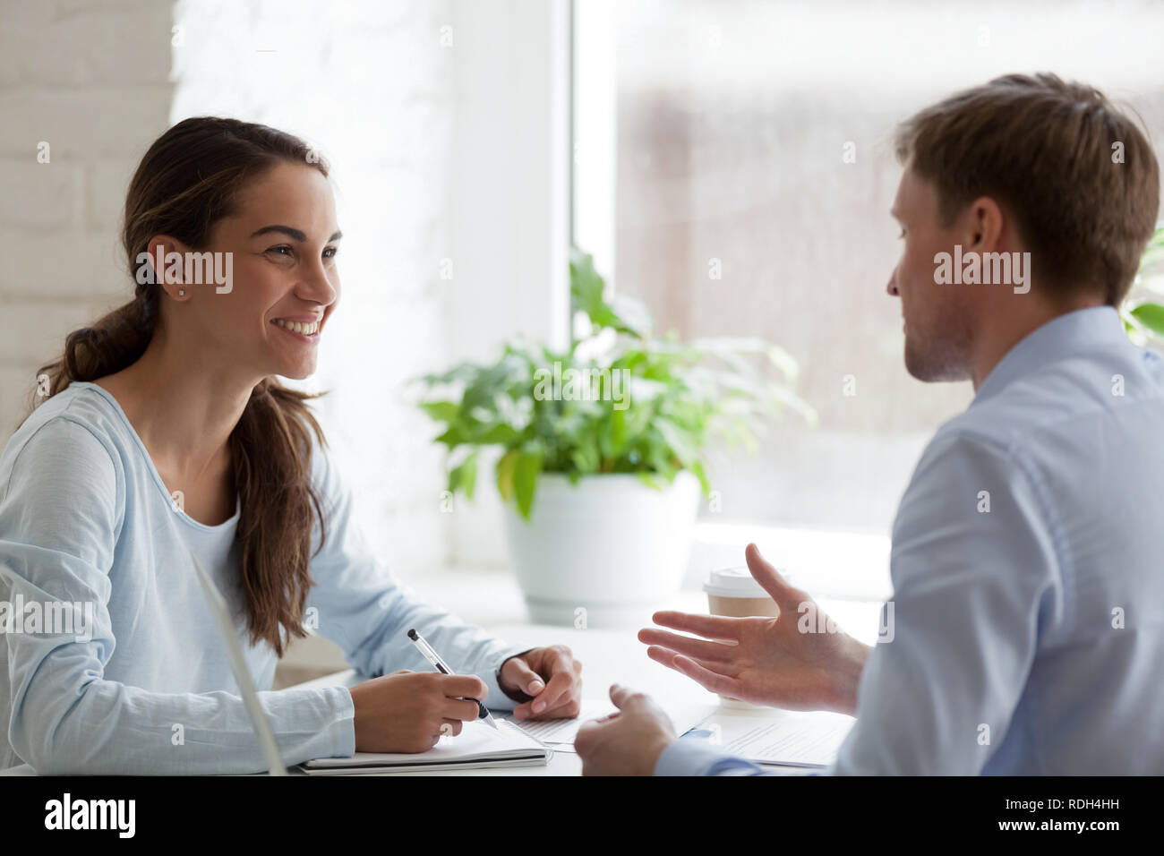 Mujer sonriente con una agradable conversación con el colega masculino Foto de stock