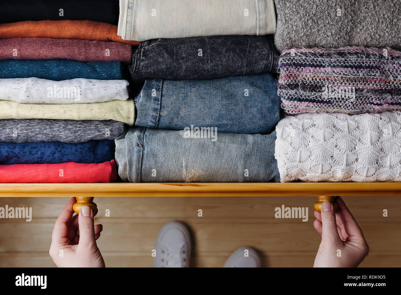 Fotografía cenital de ropa ordenado en el cajón de madera. Mujer organizar la ropa en el cajón Foto de stock