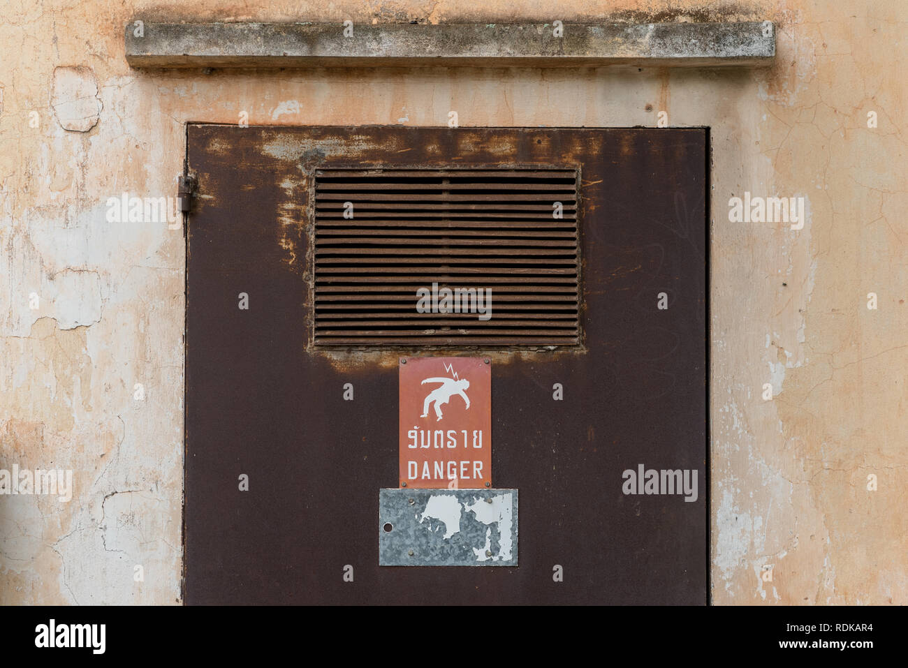 Transformador armario con la puerta oxidada y una significativa señal advierte (en laosiano & Inglés) en peligro de alta tensión. Vientiane, República Democrática Popular Lao Foto de stock