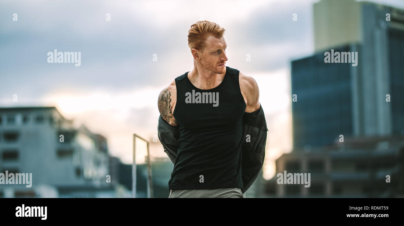 Fitness hombre preparándose para entrenar quitando su sudadera. Hombre de  cuerpo musculoso de pie en la azotea de despegar su camiseta de  entrenamiento físico Fotografía de stock - Alamy