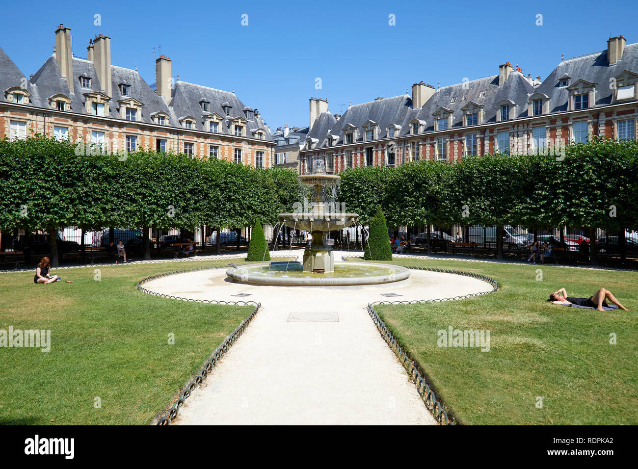 París, Francia - Julio 6, 2018: Place des Vosges con gente tomando el sol en la hierba en un día soleado de verano, el azul claro del cielo en París Foto de stock