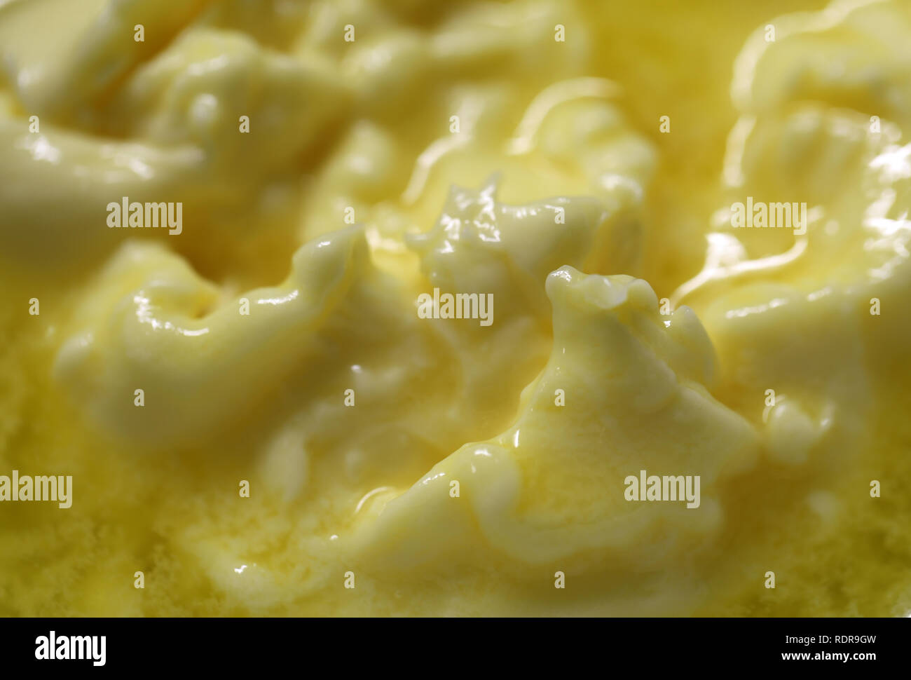Cerca de la mitad de la mantequilla derretida. En esta foto, se puede ver la superficie de amarillo mantequilla. Parece casi montañas de mantequilla y mantequilla lago. Foto de stock