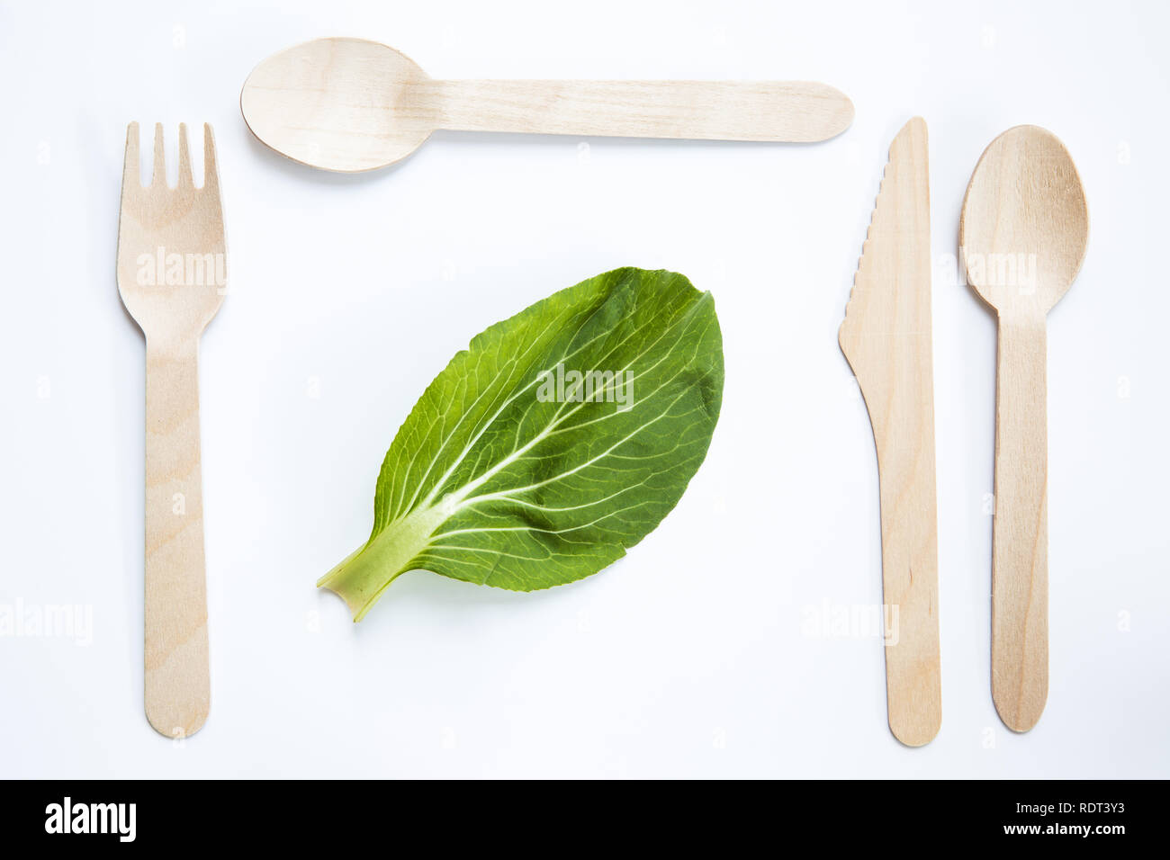 Un plano de laicos verduras frescas y comida vegetariana o vegana con ambientalmente amigable y cubiertos de madera desechable en un lugar Foto de stock