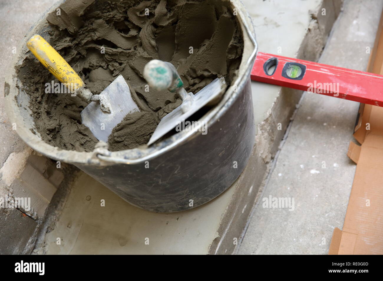 Cuchara de construcción de plástico con pegamento a base de cemento listo  para ser usado para el encolado de baldosas de cerámica Fotografía de stock  - Alamy