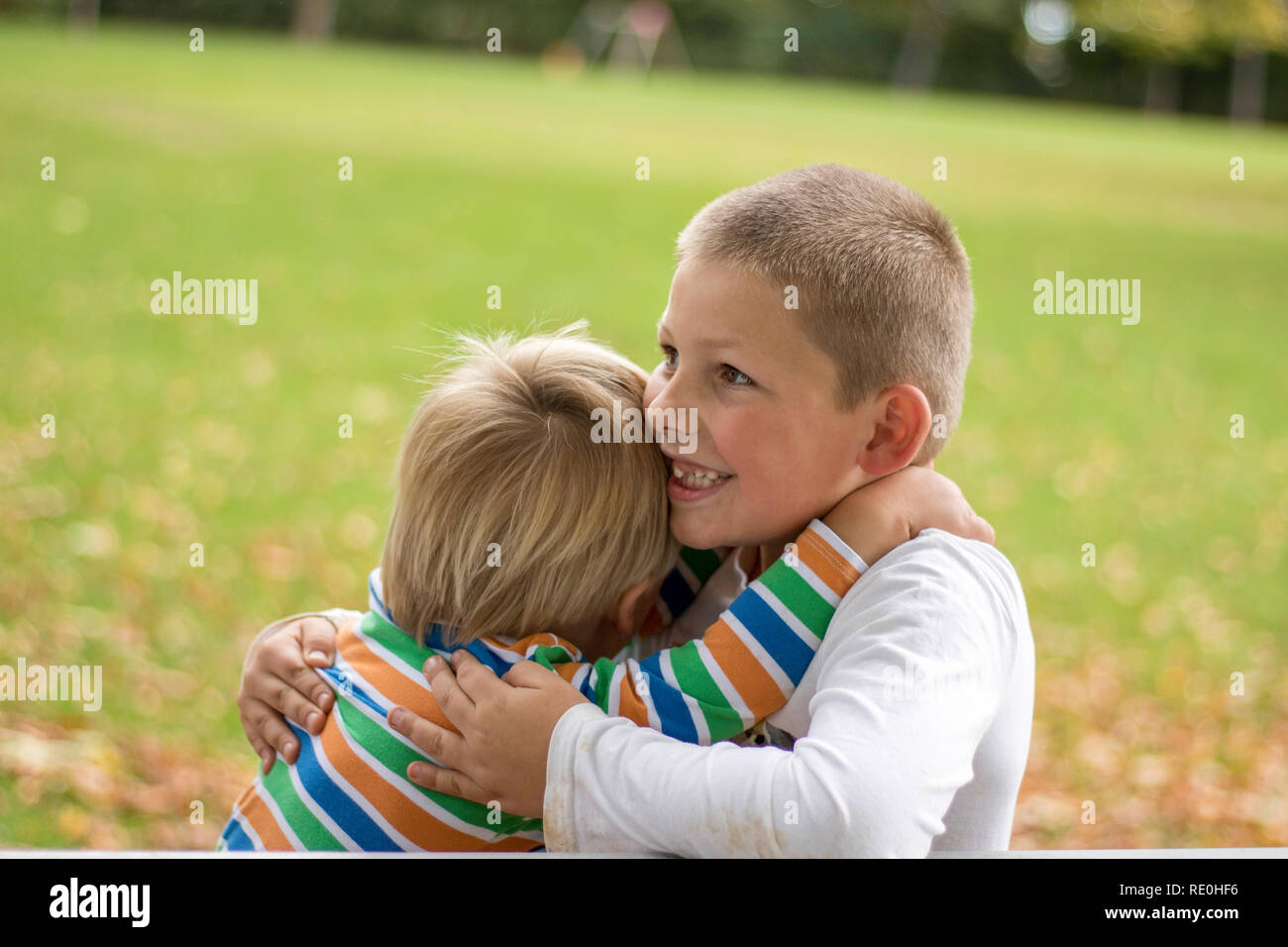 Dos chicos brtohers ocupan alrededor de los hombros en un día soleado de verano. Hermano amor. Concepto de amistad. Foto de stock