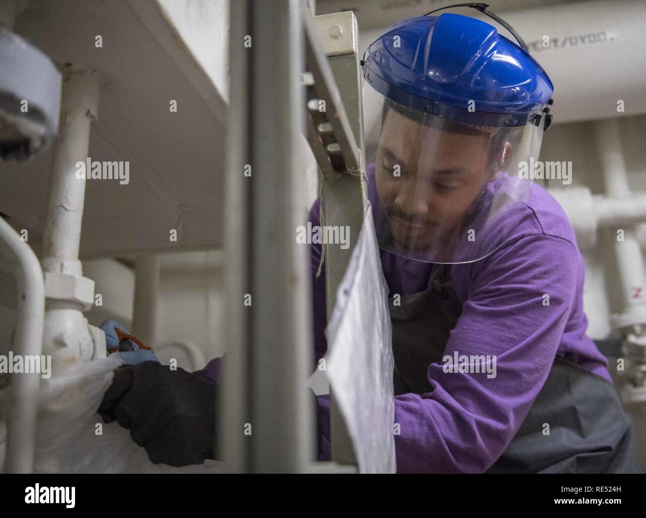 El Mar de China oriental (Ene. 1, 2018), técnico del sistema de turbina de gas (mecánica) Bombero Malik Hughes, de Louisville, Ky., drena un cabezal hidráulico tanque a bordo de la clase Arleigh Burke de misiles guiados destructor USS McCampbell (DDG 85). Es McCampbell desplegadas a la séptima Flota de EE.UU. zona de operaciones en apoyo de la seguridad y la estabilidad en la región del Indo-Pacífico. Foto de stock
