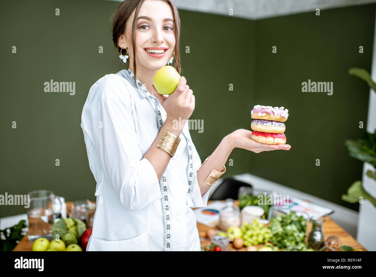 Mujer joven nutricionista en busca de Apple en la elección entre comida sana y dulce postre Foto de stock