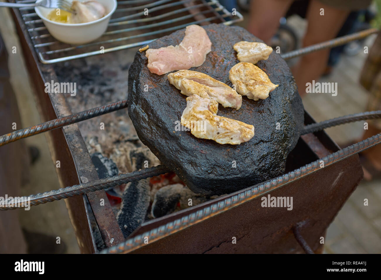 Pollo asado frito sobre un fuego real sobre una roca natural. Deliciosas comidas en un brasero. Foto de stock