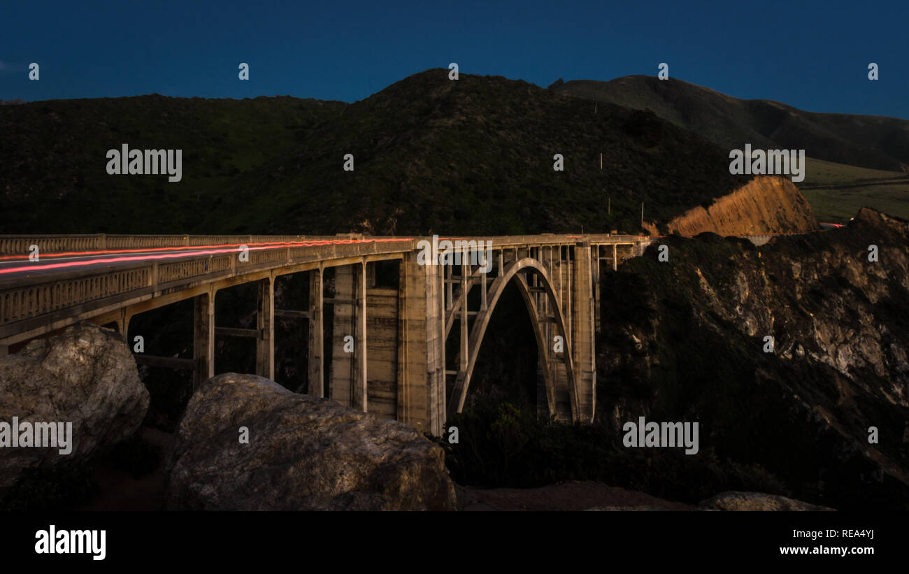 Coches cruzar la Bixby Creek Bridge al atardecer en Big Sur, California. Foto de stock