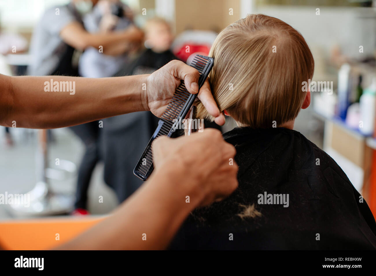 Crop barber haciendo corte de pelo para chico Foto de stock