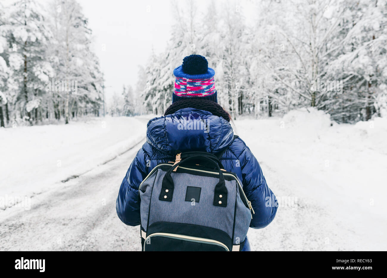 Estilo de viaje. Mujer joven con mochila en invierno con nieve road en Suecia Foto de stock