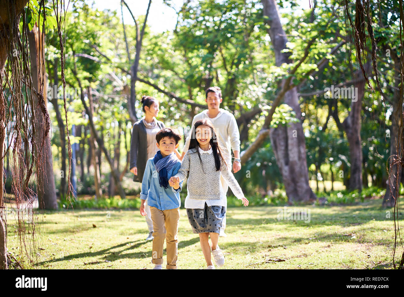 Familia con dos niños asiáticos paseos relajantes a divertirse en el parque feliz y sonriente. Foto de stock