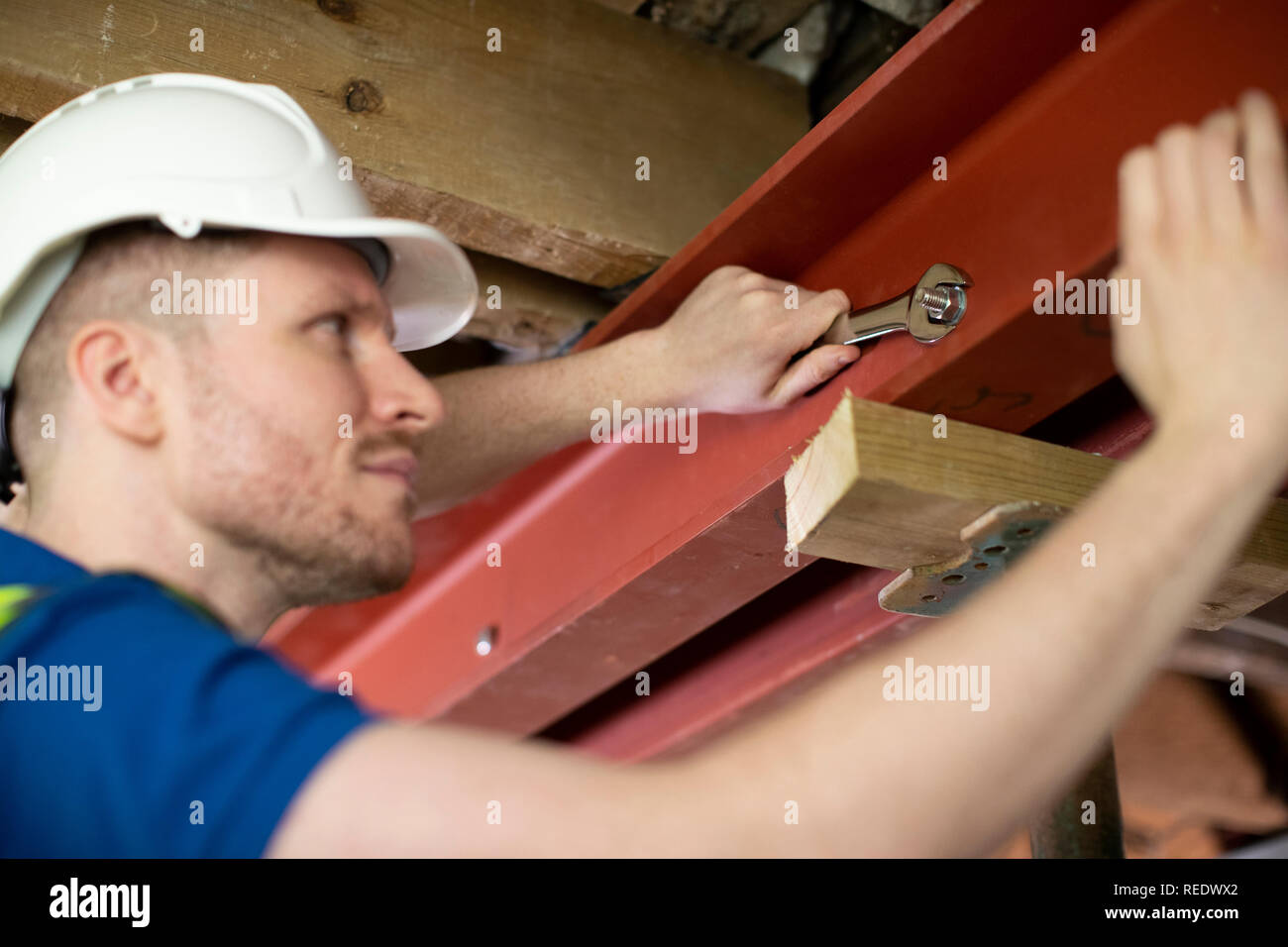 Trabajador de la construcción de la viga de soporte de acero de montaje en techo Casa renovada Foto de stock