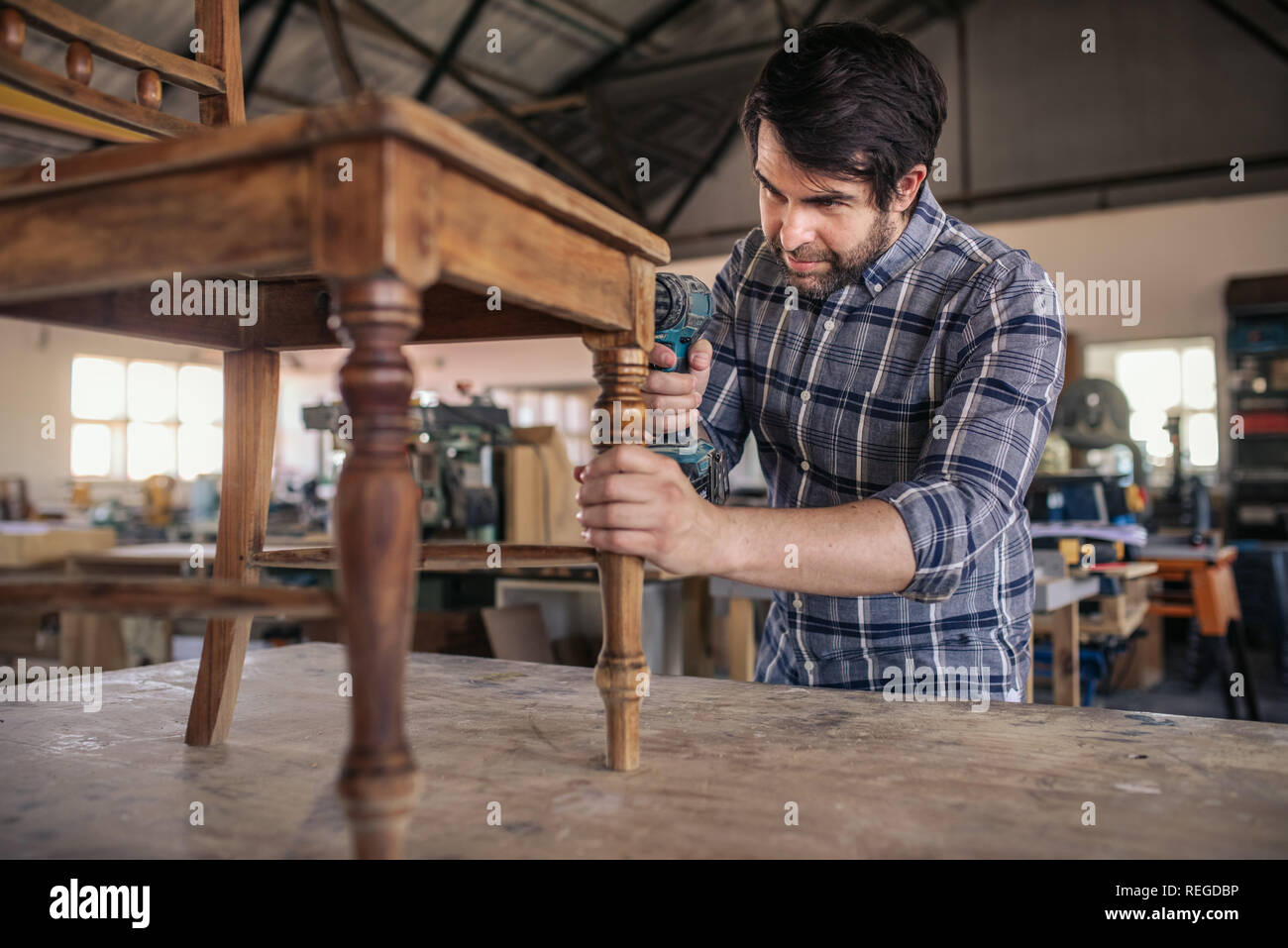 Tallista atornillar juntos una silla en su taller de carpintería Foto de stock