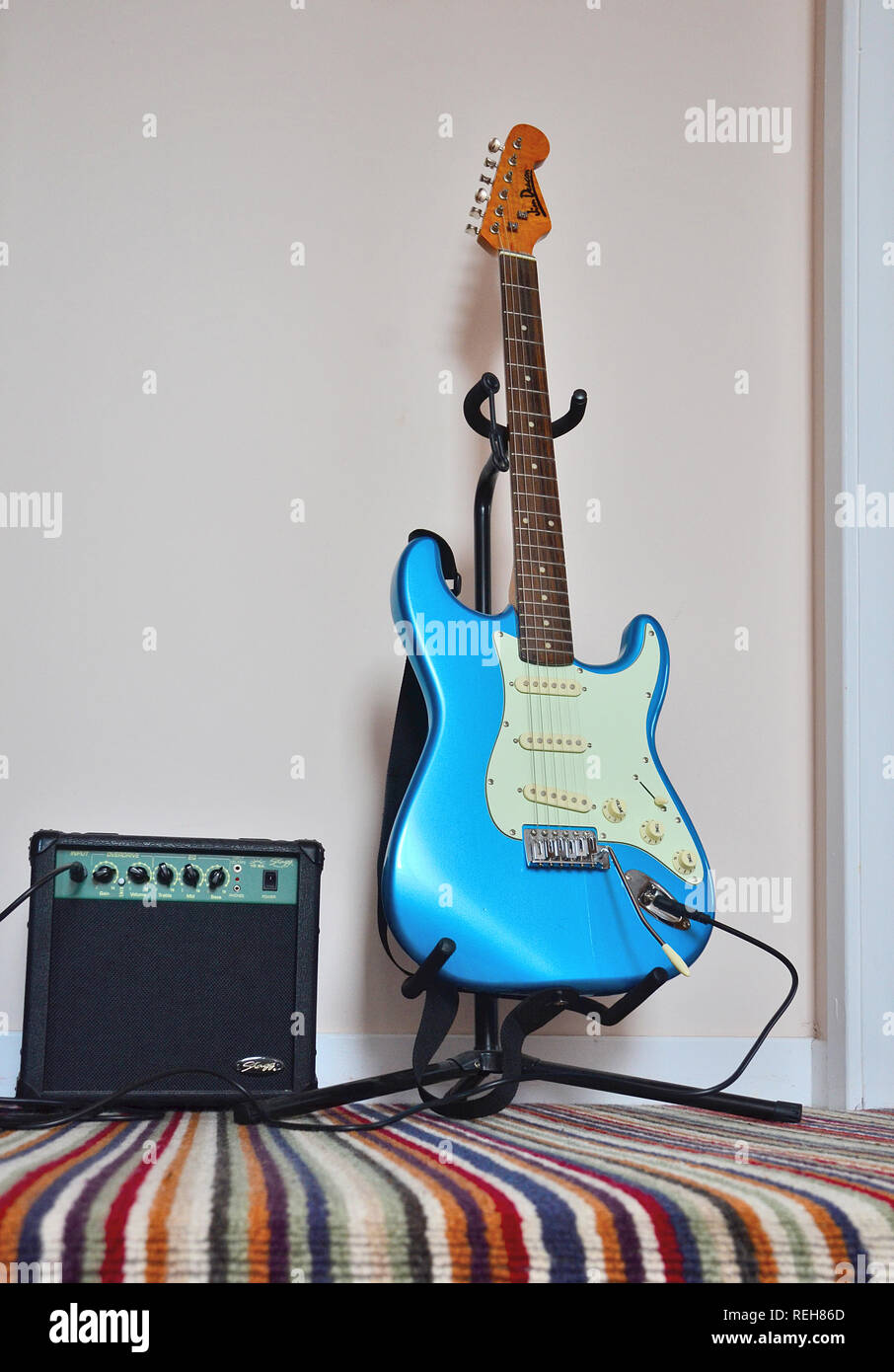 Una guitarra eléctrica azul sentado en el pedestal con amplificador. Foto de stock
