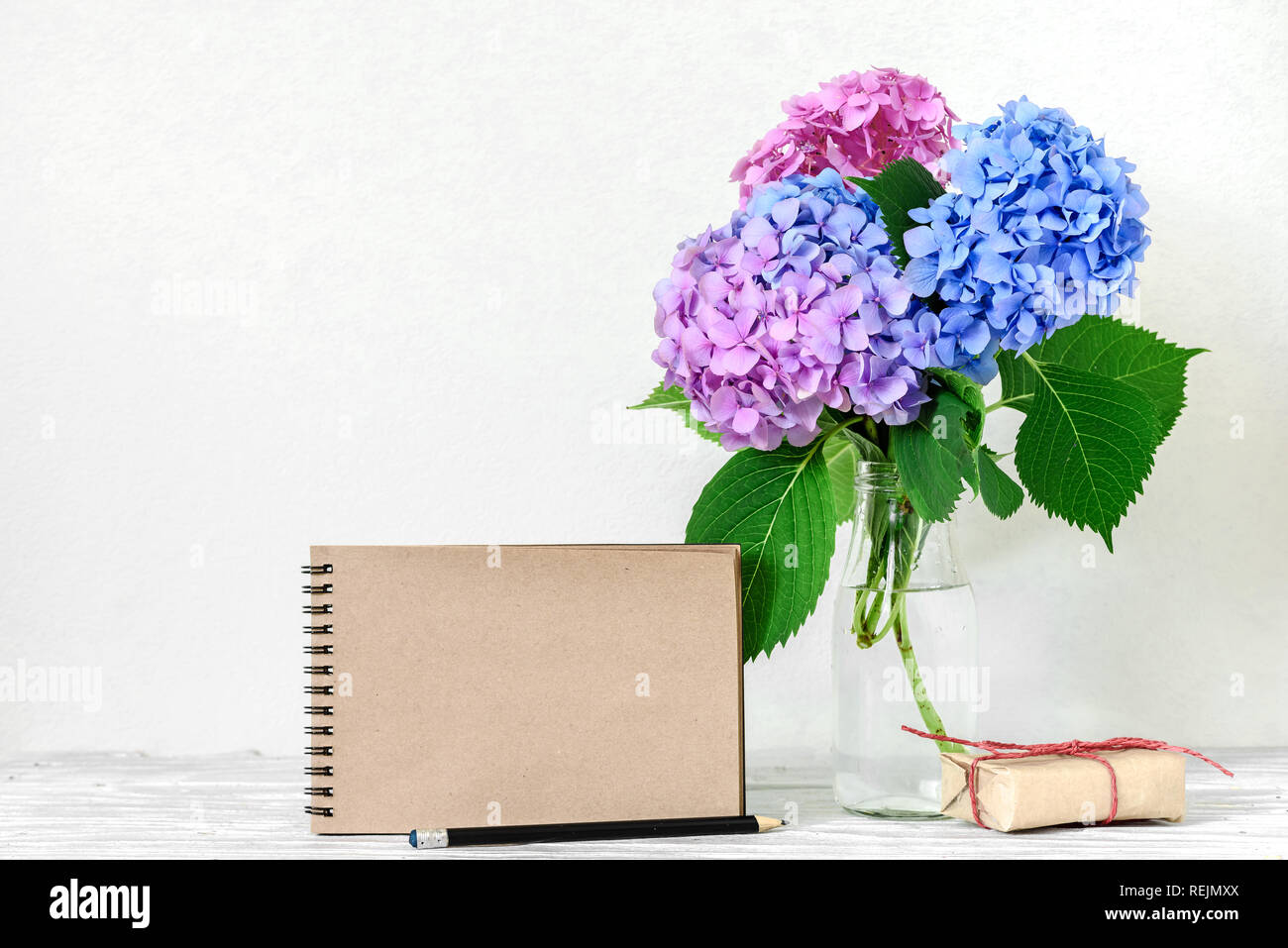Maqueta creativa con un precioso ramo de rosas y azules Hydrangea Las  flores, caja de regalo blanco y hipster portátil con lugar para el texto.  vacaciones o wedd Fotografía de stock -