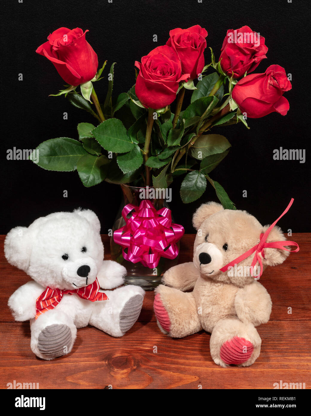 Dos lindos peluches osos de peluche con rosas rojas en jarrón y rosa arco  sobre mesa de madera sobre fondo oscuro. Día de San Valentín, Día de las  madres, Semana Santa, Navidad,