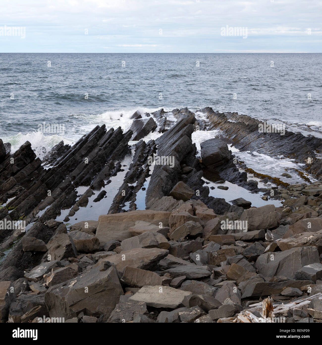 Cerca de la costa estratificado Marte en la península de Gaspé de Quebec, Canadá. Las olas rompen contra las rocas. Foto de stock