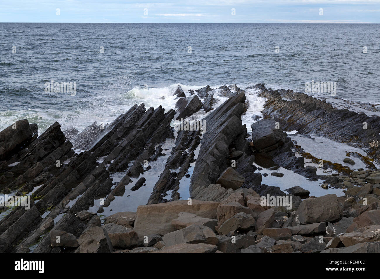 Cerca de la costa estratificado Marte en la península de Gaspé de Quebec, Canadá. Las olas rompen contra las rocas. Foto de stock