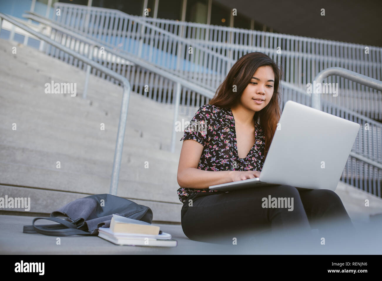 Estudiante universitario de Asia utilizando un ordenador portátil en algunos campus escaleras Foto de stock
