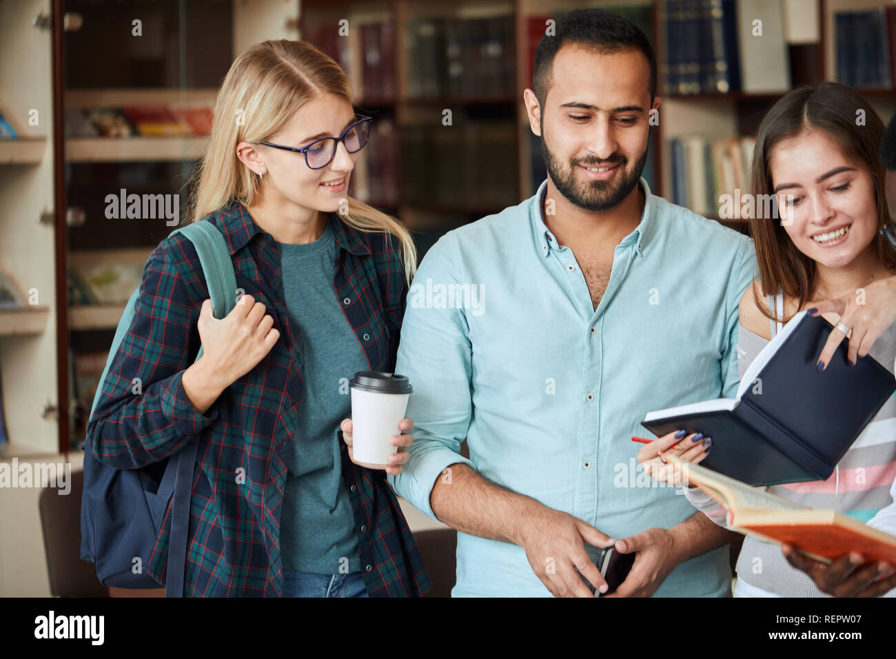 Retrato multicultural de jóvenes amigos leer libros juntos en la biblioteca Foto de stock