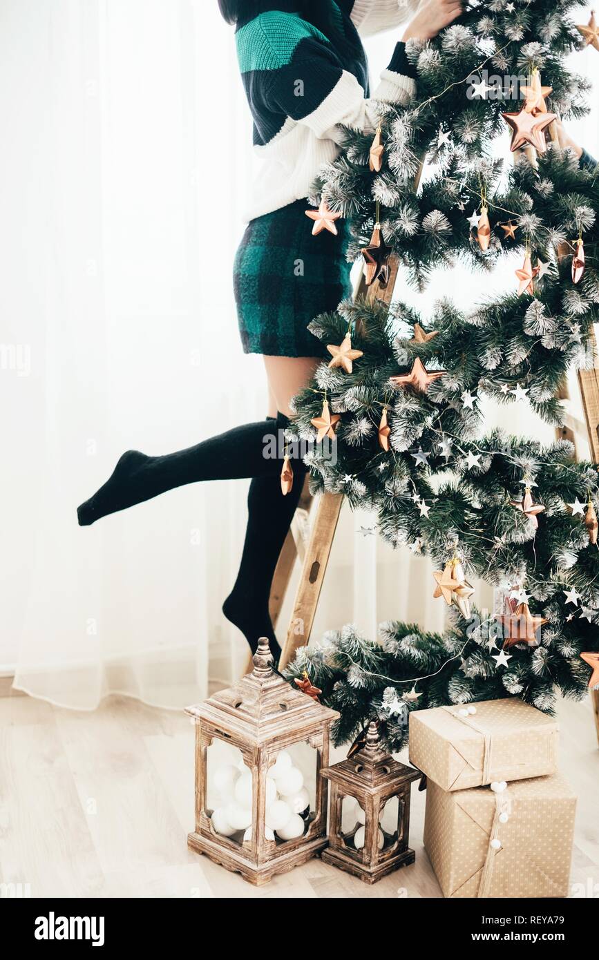 Horario de invierno en casa, joven suéter caliente en invierno decora un árbol de Navidad. Foto de stock