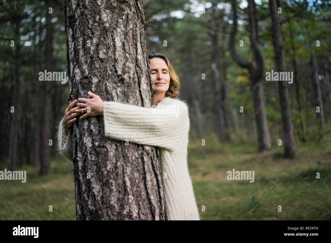 Mujer abrazando el árbol en el bosque Foto de stock