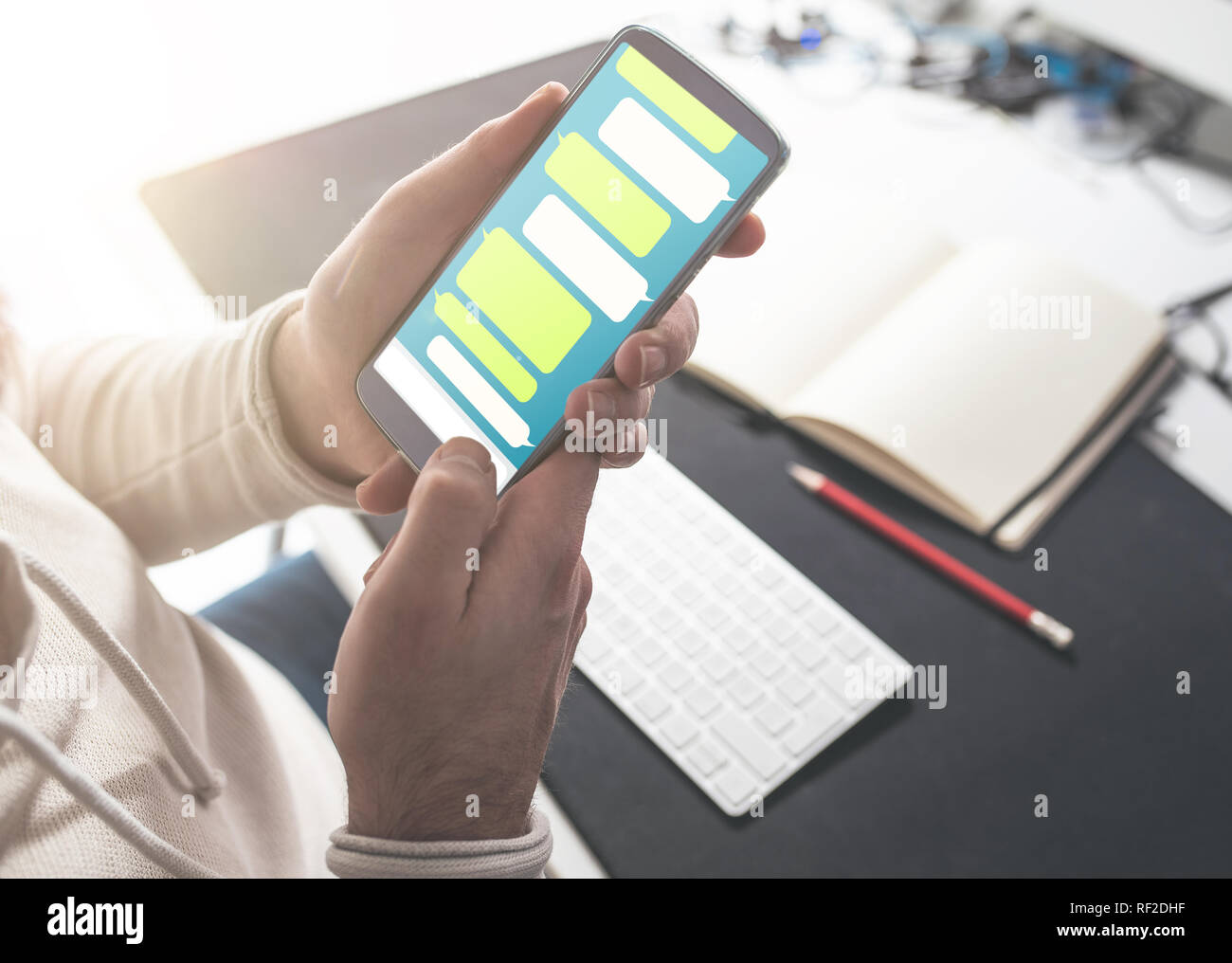 La persona utilizando messaging app mock-up en smartphone en escritorio de oficina Foto de stock
